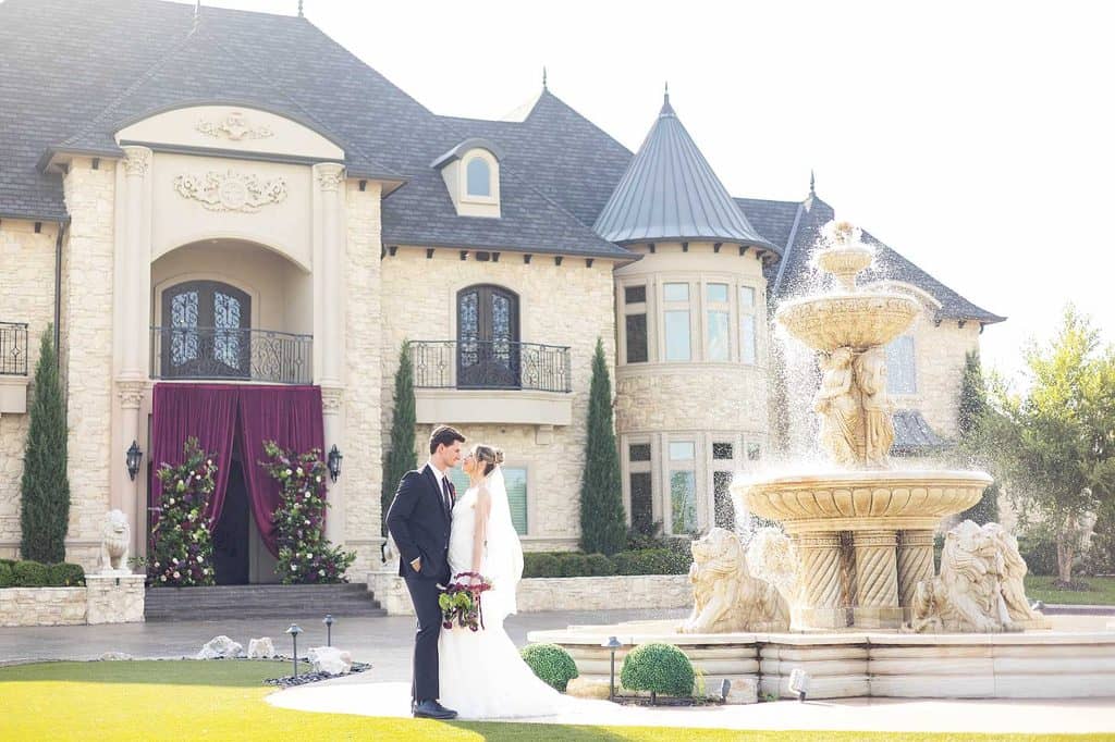 bride and groom standing together next to a fountain in front of the knotting hill place wedding venue